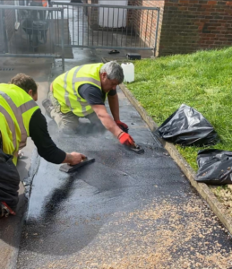 Two workers in yellow vests are engaged in cleaning mastic asphalt, focusing on waterproofing for enhanced longevity.