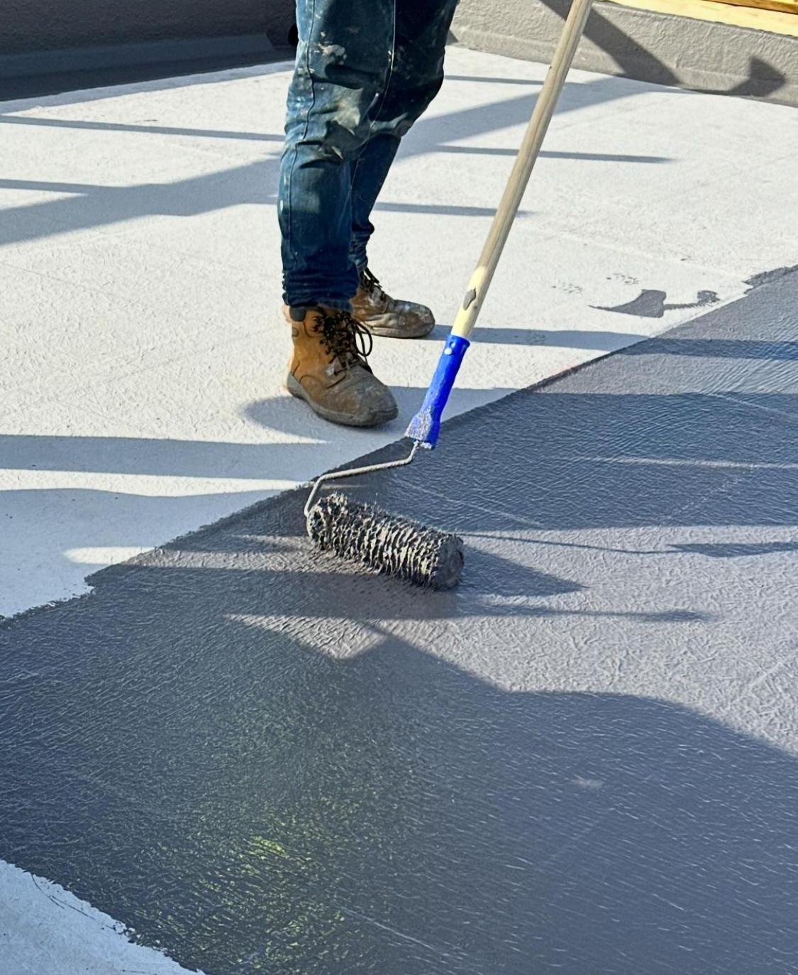 A man using a roller to paint a roof, showcasing Advanced Liquid Roofing services in London.