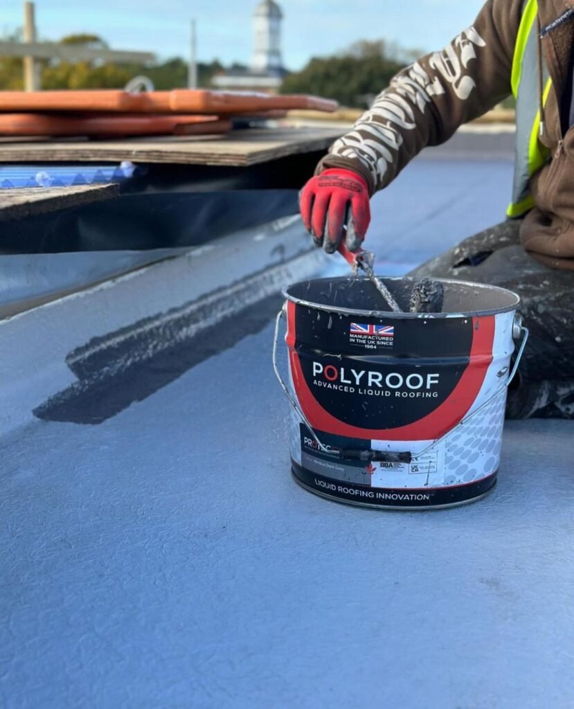 A man applies liquid roofing to a roof using a paint roller in London.