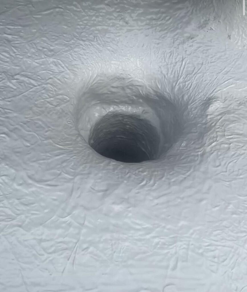 A close-up of a hole in the ground featuring another hole, showcasing liquid roofing work in London.