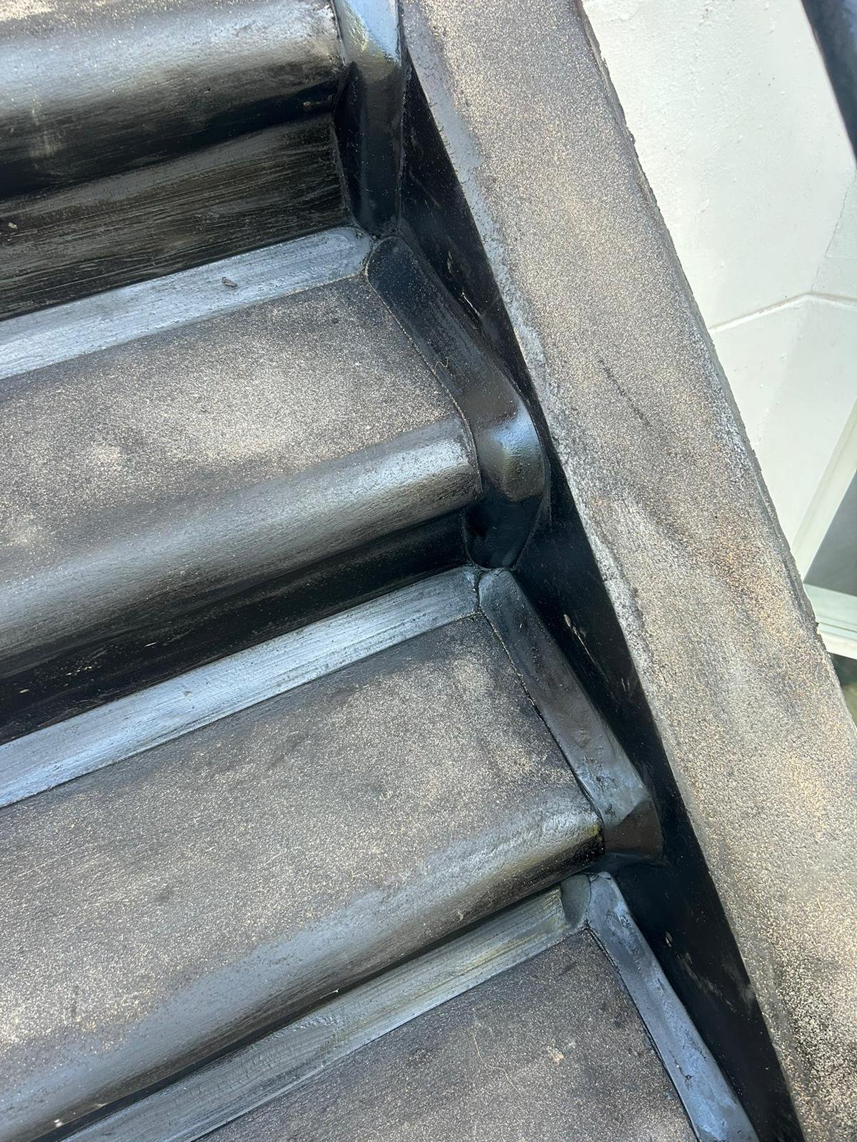 Close-up image of repaired steps with black mastic asphalt applied on the surface and edges, showing the smooth texture and defined corners of the step edges.