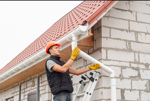 A gutter contractor repairs a house's gutter, ensuring proper drainage and maintenance for the home.