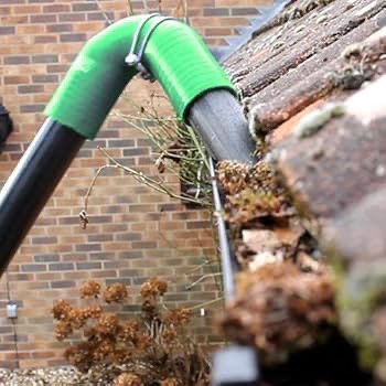 A green hose connected to a roof, illustrating gutter cleaning services in London.