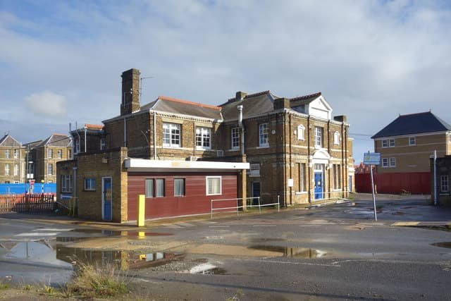 Old brick building with puddles in an empty lot under a cloudy sky.